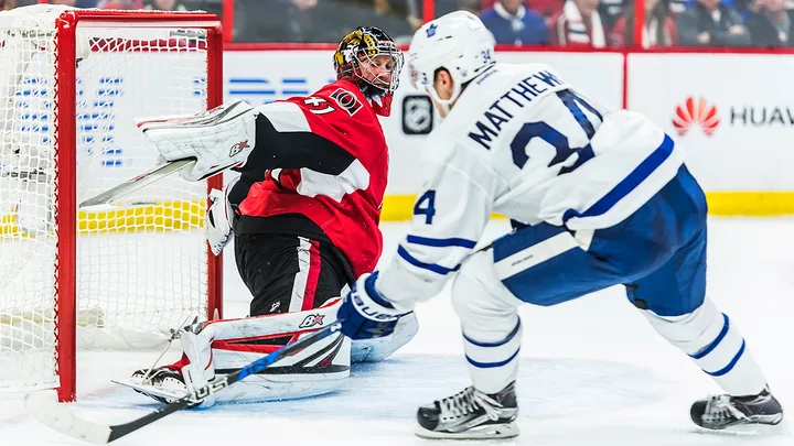 An ice hockey forward approaching a goalkeeper beside the net